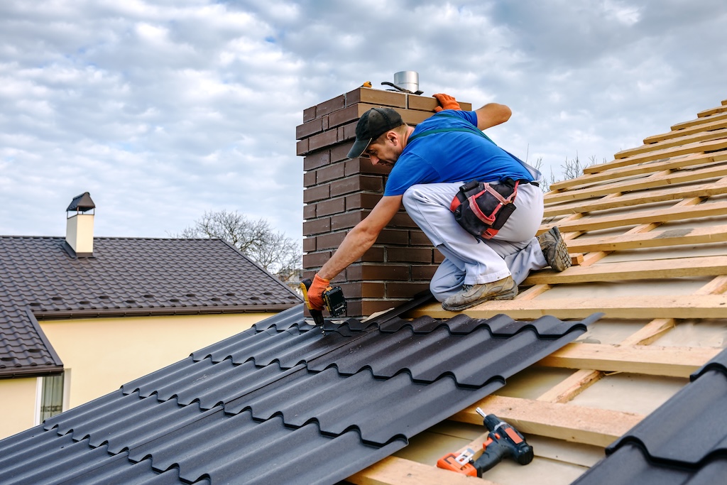a professional roofer with electric screwdriver covers repairs the roof